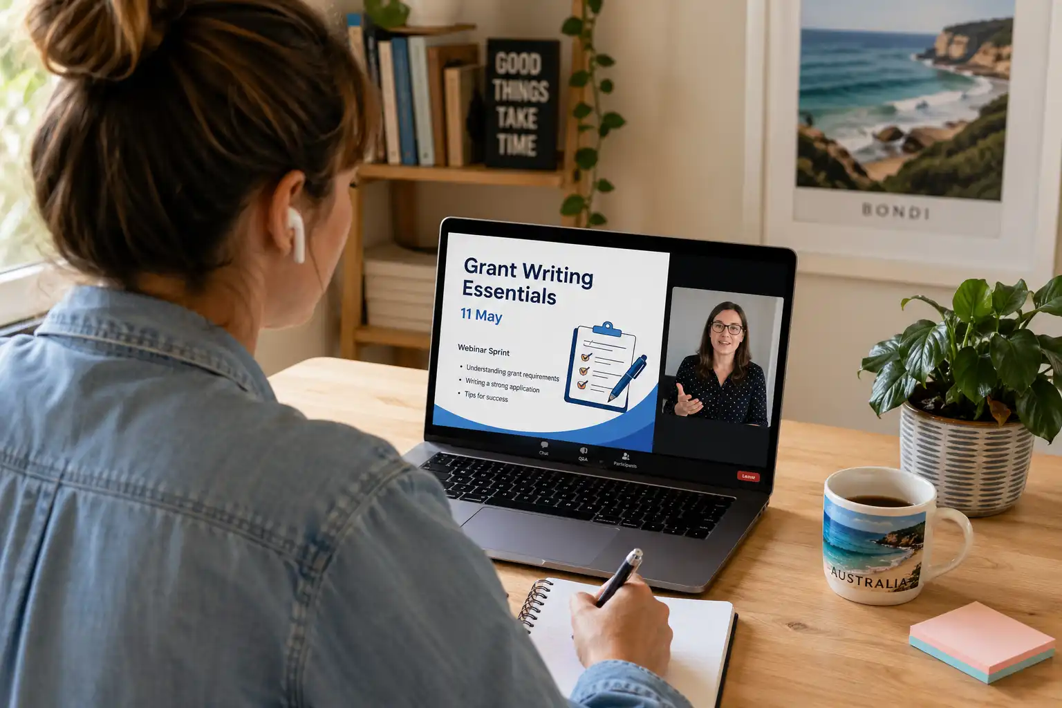 Person sitting at desk with pen and paper watching workshop on laptop.